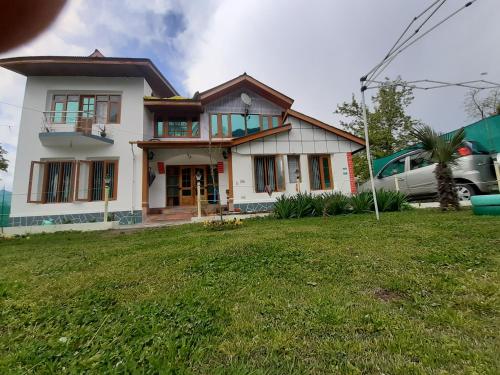 a house with a green lawn in front of it at Rose Bowl Guest House Homestay in Bāgh Chandpura