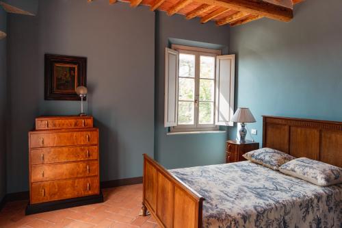 ein Schlafzimmer mit einem Bett, einer Kommode und einem Fenster in der Unterkunft Villa Cosmiana suites in Peccioli