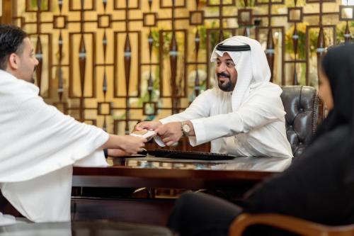 a man shaking hands with a woman at a table at Makkah Clock Royal Tower, A Fairmont Hotel in Makkah