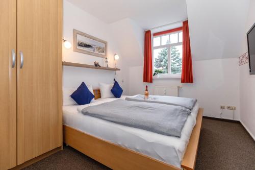 a bedroom with a bed with blue pillows and a window at Brücken-Butze Whg 12 Villa Strandburg in Kühlungsborn