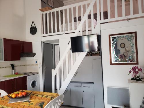 une cuisine avec un escalier, une table et une télévision dans l'établissement Confortable maison dans résidence avec piscine, 100 m de la plage, à Valras-Plage