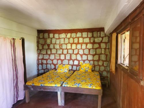 ein kleines Zimmer mit einem Bett mit gelben Kissen in der Unterkunft villa vanille in Tôlagnaro