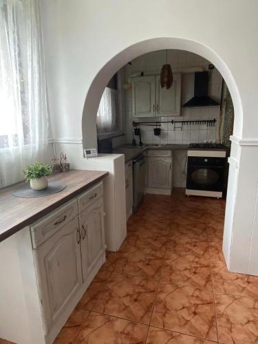 a kitchen with white cabinets and an archway in it at Magyar Lovasvendégház in Szilvásvárad