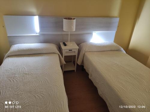 a room with two beds and a table with a lamp at Toño el Alguacil in Selaya