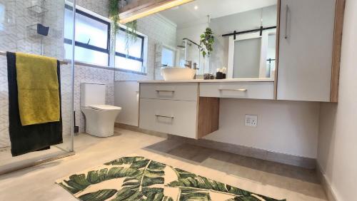ein Badezimmer mit einem Waschbecken, einem WC und einem Spiegel in der Unterkunft Executive Suites Brackenhurst in Alberton