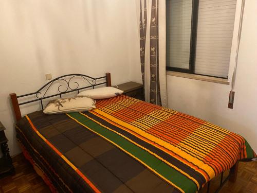 ein Schlafzimmer mit einem Bett mit einer Orange- und Gründecke in der Unterkunft casa Sao bras Alportel Miguel in São Brás de Alportel