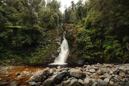 a waterfall in the middle of a river at Rimu View 1 by Tiny Away in Hokitika
