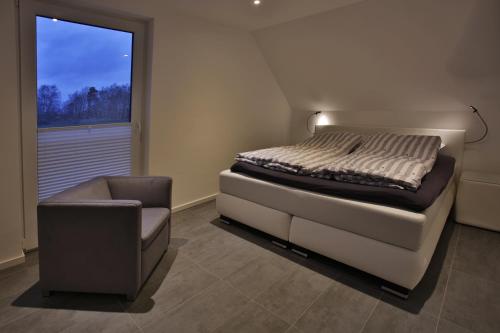 ein Schlafzimmer mit einem Bett, einem Stuhl und einem Fenster in der Unterkunft Exklusives FERIENHAUS im Yachthafen Peenemünde - mit Seeblick in Peenemünde