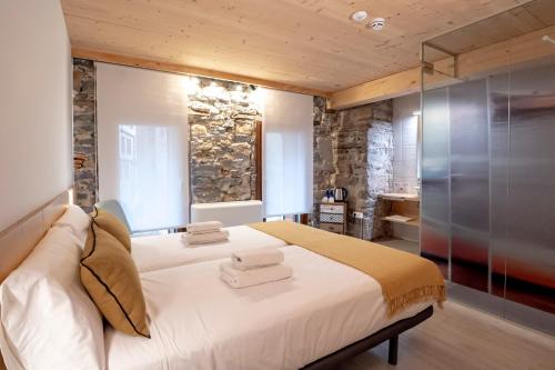 a bedroom with a large white bed and a stone wall at Aristondo Pentsioa in Getaria