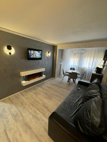 a living room with a couch and a tv on a wall at David Apartament’s in Buzău