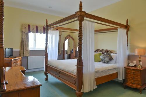 a bedroom with a four poster bed and a desk at Southview Park Hotel in Skegness