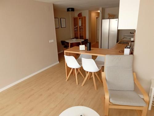 eine Küche mit einem Holztisch und weißen Stühlen in der Unterkunft Apartamento Eman in Villajoyosa