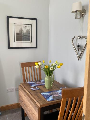 a dining room table with a vase of flowers on it at Highmains in Dumfries