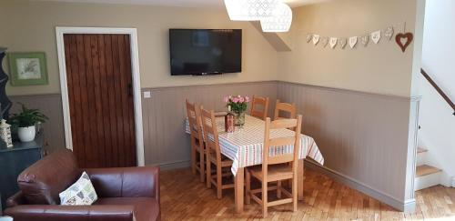 a dining room with a table and chairs and a television at Vale View Cottages - The Stables in Prestatyn