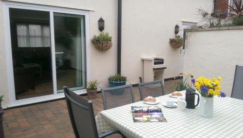 a table with a white table cloth and flowers on a patio at Vale View Cottages - The Stables in Prestatyn