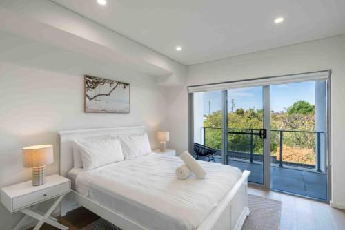 um quarto com uma cama branca e uma grande janela em Relax at Ridgewaters em Kiama