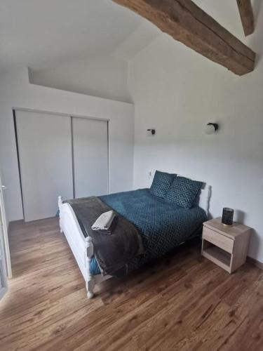 a bedroom with a bed and a wooden floor at La grange de Pierrot in Saint-Bazile