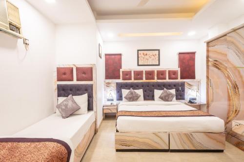 two beds in a room with white walls at Hotel Cosmo Karol Bagh in New Delhi