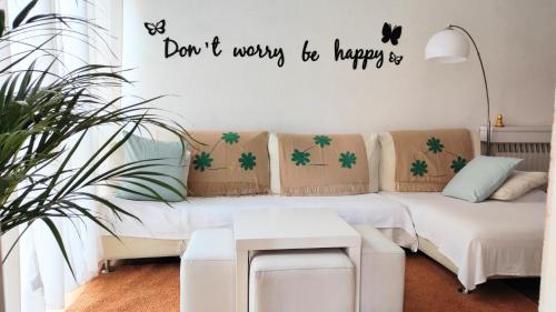 a living room with a couch and a sign that says dont worry be happy at Apartamento Cartellà 4 habitaciones in Barcelona