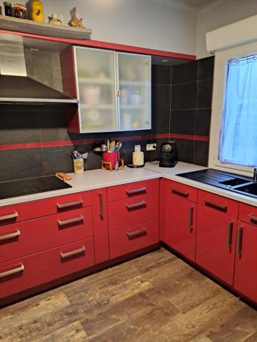 una cucina rossa con armadi rossi e una finestra di maison de vacances SOREDE 5 KMS ARGELES SUR MER a Sorède