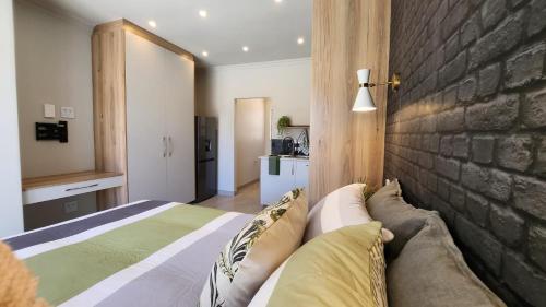 ein Schlafzimmer mit einem Bett und einer Ziegelwand in der Unterkunft Executive Suites Brackenhurst in Alberton