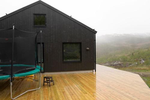 uma casa preta com piso de madeira e um deque em Cozy Retreat and danish design in Nature's Splendor, Sogn, Norway, Jacuzzi-option available em Sogndal