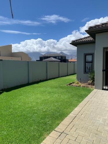 a yard of a house with a fence and green grass at Family Friendly Home in Gordonʼs Bay