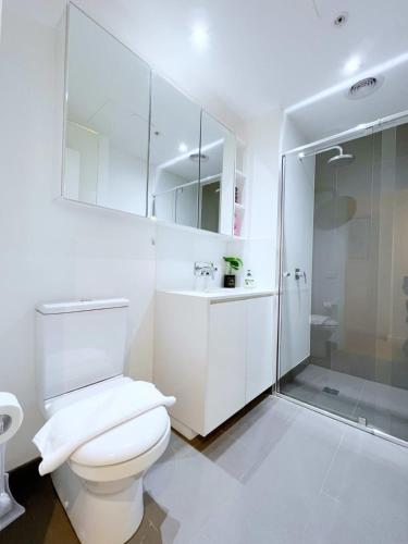 a white bathroom with a toilet and a shower at Beautiful 1B1B Prahran apartment in Melbourne