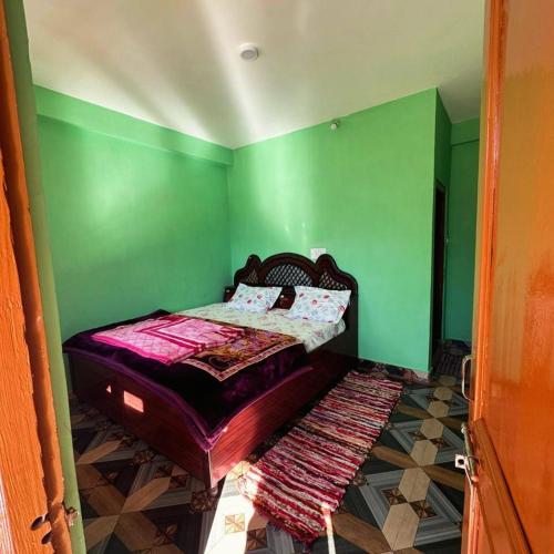 a bedroom with a bed with green walls at Vigyan Guest House Tosh in Tosh