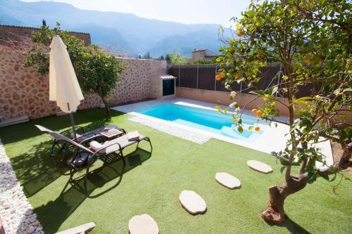 un patio trasero con piscina y sombrilla en Ground floor with garden, swimming pool and private parking, en Sóller