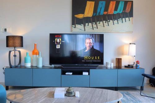 a tv sitting on a blue cabinet in a living room at 2BR Bright Coastal Haven - Al Reem Escape in Abu Dhabi