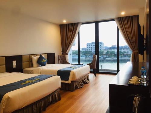 a hotel room with two beds and a large window at Golden Palm HaLong Hotel in Ha Long