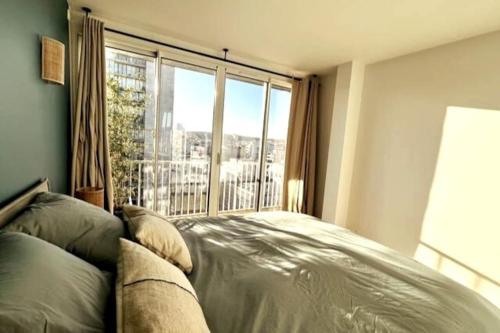 une chambre avec un lit et une grande fenêtre dans l'établissement Bright & cosy appart, balcony, à Boulogne-Billancourt
