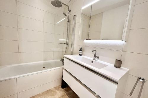 une salle de bain blanche avec un lavabo et une baignoire dans l'établissement Bright & cosy appart, balcony, à Boulogne-Billancourt