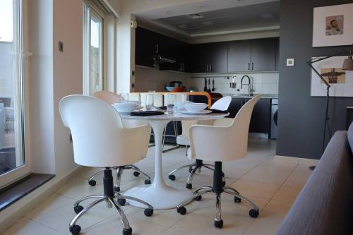 a kitchen with white chairs and a table in it at 2BR Bright Coastal Haven - Al Reem Escape in Abu Dhabi