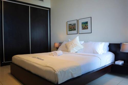 a bedroom with a large bed with white sheets at 2BR Bright Coastal Haven - Al Reem Escape in Abu Dhabi