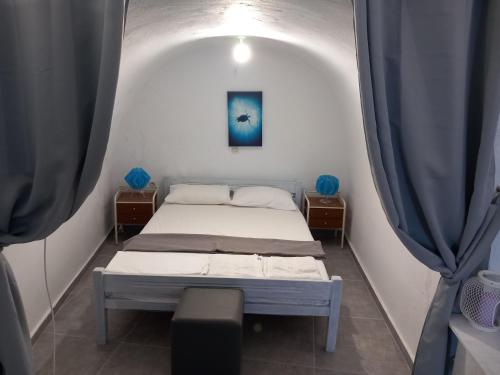 a bed in a room with two blue curtains at VI STA FINIKIAS VILLA in Oia