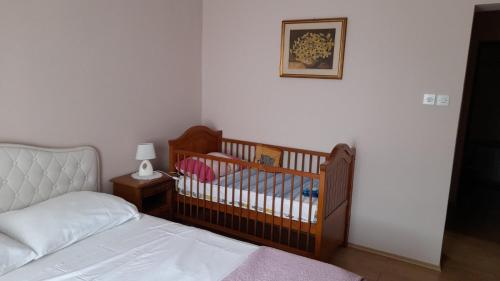 a bedroom with a crib and a table with a lamp at Family Apartment Tonko with King's Bed in Matulji