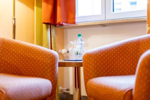 ヴュルツブルクにあるホテル アルター クラネンの椅子2脚、テーブル、ボトル入り飲料水2本