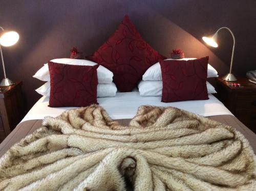 a bed with a blanket on it with red pillows at Lakefront Lodge in Te Anau