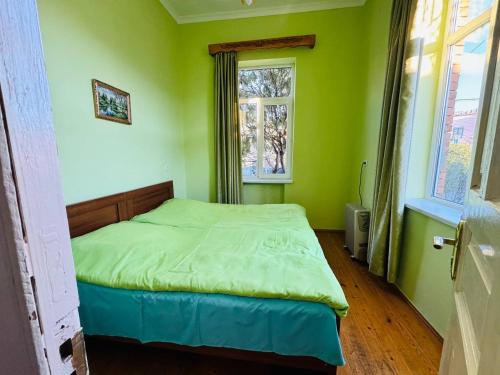 Schlafzimmer mit einem Bett mit grünen Wänden und einem Fenster in der Unterkunft GUEST HOUSE "BUBU" in Kutaissi