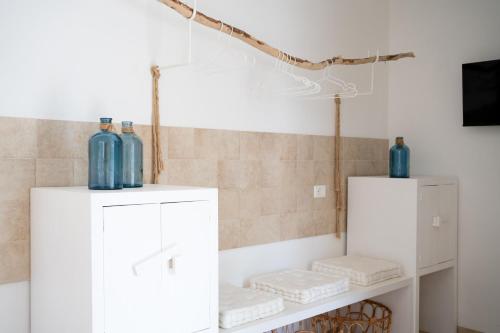 - deux bouteilles bleues au-dessus des armoires blanches dans la salle de bains dans l'établissement Oltre gli Ulivi, à Ostuni