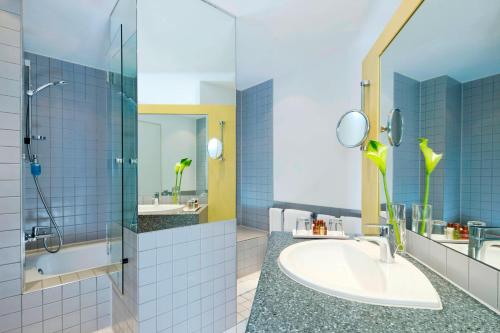 a bathroom with a sink and a shower at Sheraton Hannover Pelikan Hotel in Hannover
