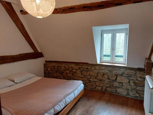 une chambre avec un lit et un mur en pierre dans l'établissement La Belangerie, à Saint-Loup