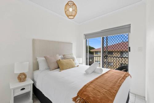 a white bedroom with a large bed and a window at Penthouse in Gold Coast in Gold Coast