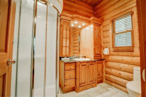 a bathroom with a toilet and a sink in a log cabin at Chalet Authentik 27 - Hot tub, Pools, Lake & Resort in Mille-Isles