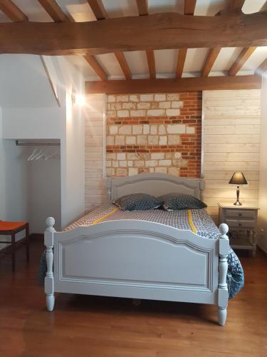een wit bed in een kamer met een bakstenen muur bij Le Côte d'Albâtre in Tourville-la-Chapelle