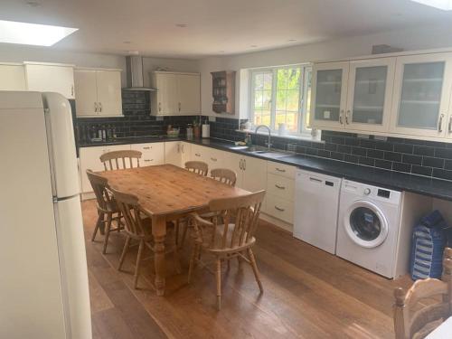 uma cozinha com uma mesa de madeira com cadeiras e uma máquina de lavar roupa em Relaxing country cottage bungalow em Yaxley