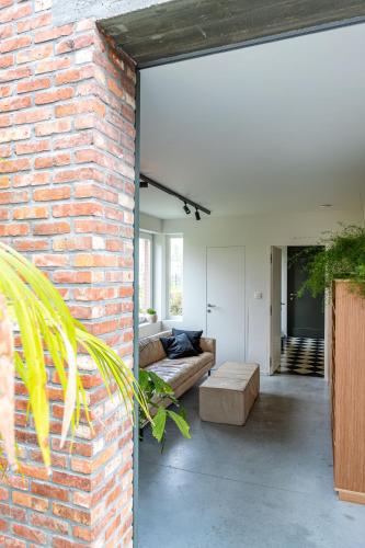 a living room with a brick wall and a couch at stek&stoof in Sint-Pauwels