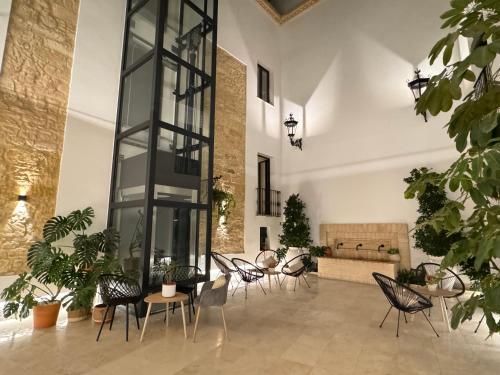 Habitación grande con sillas, mesas y una pared de cristal. en Casa Boutique Navarro, en Montilla